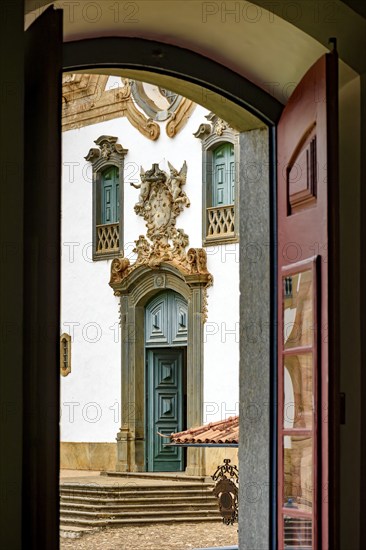 Baroque church front seen through the window of an old colonial-style house in the city of Mariana