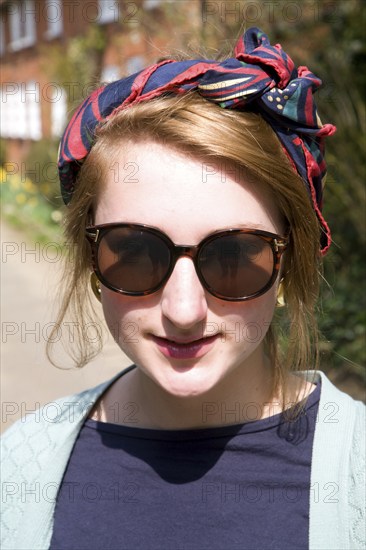 Model released head and shoulders portrait of teenage girl wearing sunglasses and head scarf