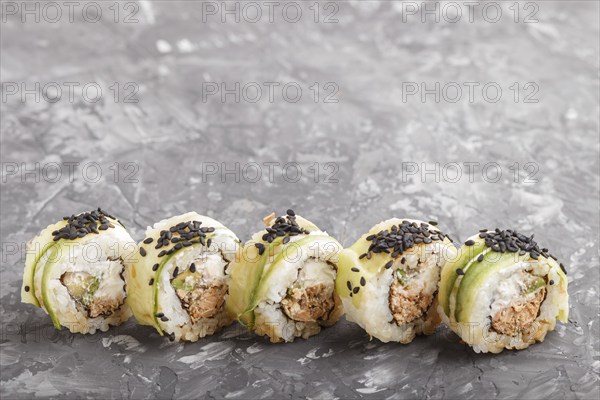 Japanese maki sushi rolls with tuna, cucumber, black sesame, cheese on black concrete background.