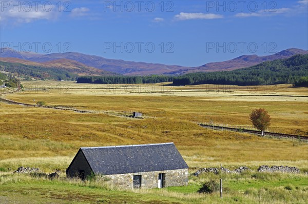 Small stone house on a wide, grassy plain under a clear blue sky, autumn, October, Highlands,