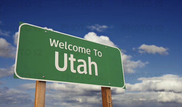 Welcome to utah green road sign over blue sky with some clouds