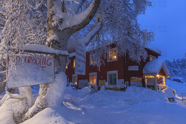 Illuminated Swedish red wooden house, shop, snow, twilight, winter, Porjus, Lapland, Sweden, Europe