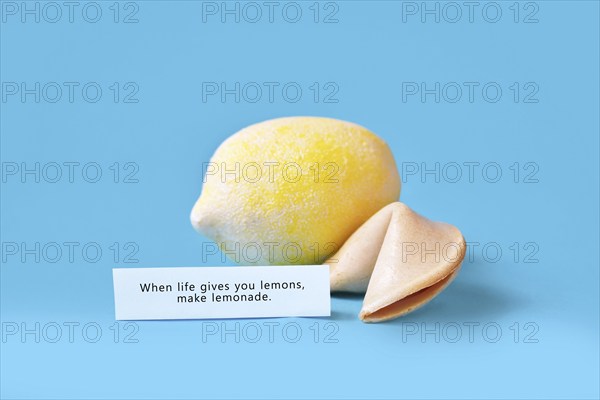 Fortune cookie with motivational text on paper saying 'When life gives you lemons, make lemonade'