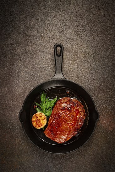 Grilled rib eye steak, in a cast-iron skillet, top view, homemade, no people