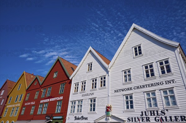 Traditional wooden houses under a blue sky with pitched roofs and multiple windows in a sunny old