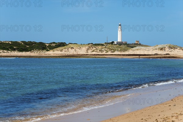 Sandy beach beach with lighthouse in the background, clear blue sea and bright dunes, Faro de