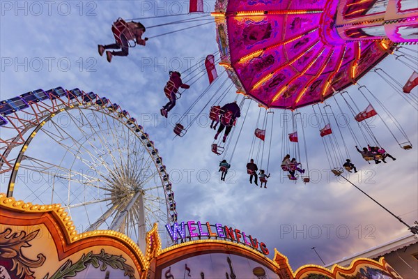 Chain carousel and Ferris wheel in the evening. 177th Cannstatter Volksfest at the Cannstatter