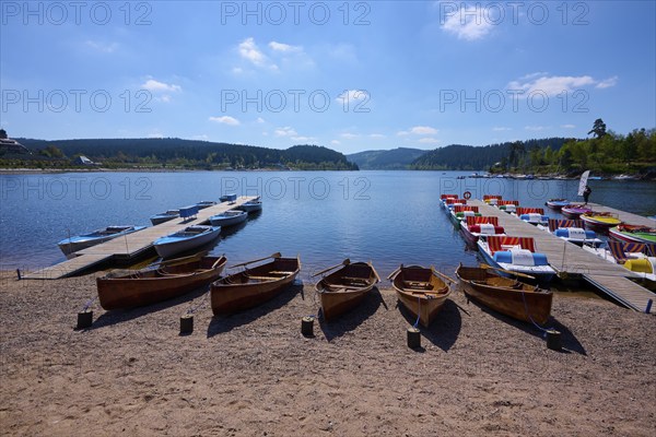 A picturesque scene with colourful pedal boats and wooden boats on a jetty in front of the