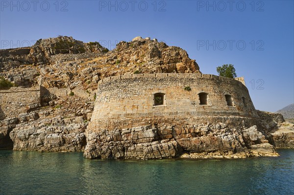 Ruins of an ancient fortress on a coastal rock formation with clear sky and sea, Venetian sea