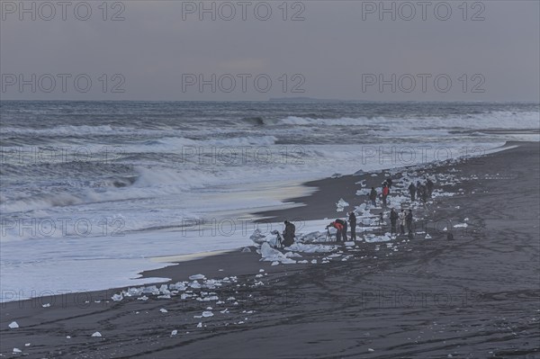 Tourists photographing ice floes on the beach, waves, sea, clouds, winter, Diamond Beach,