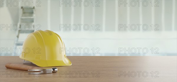 Yellow hard hat and hammer resting on a wood surface in front of drywall and ladder banner