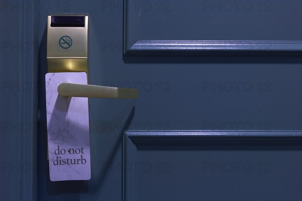 Blue painted door with 'Do Not Disturb' sign and gold-coloured handle in a hotel