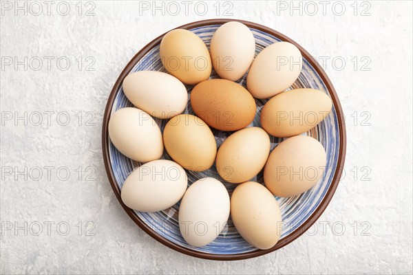 Pile of colored chicken eggs on plate on a gray concrete background. top view, flat lay, close up