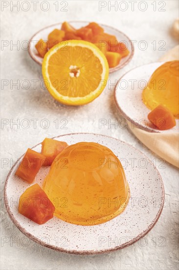 Papaya and orange jelly on gray concrete background and orange linen textile. side view, flat lay,
