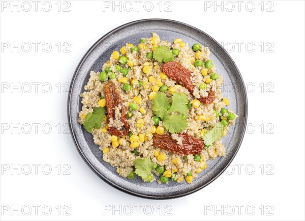 Quinoa porridge with green pea, corn and dried tomatoes on ceramic plate isolated on white