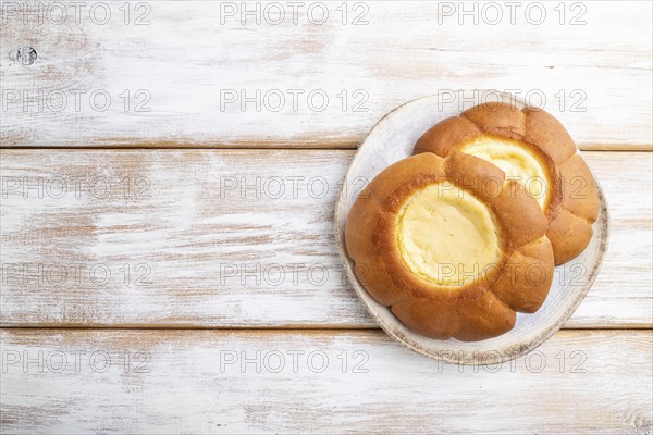 Sour cream bun on a white wooden background. top view, flat lay, copy space