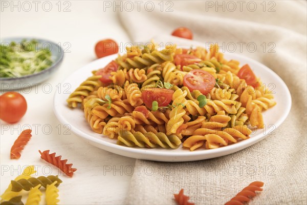 Tortiglioni semolina pasta with tomato and microgreen sprouts on a white wooden background and