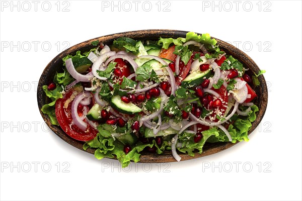 Salad of fresh vegetables, cucumbers, tomatoes, red onions, with nuts and pomegranate seeds, top