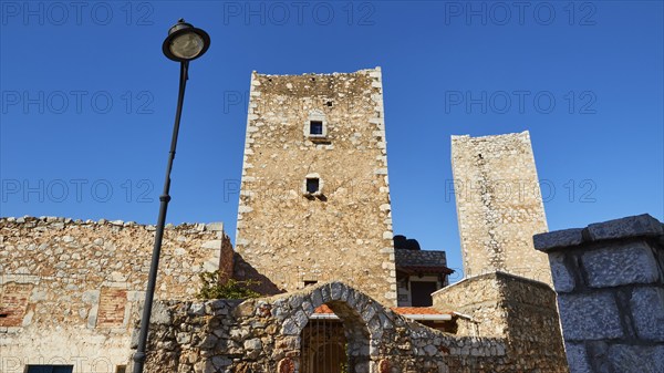 Historic stone towers next to a street lamp in a Mediterranean village, Flomochori, residential