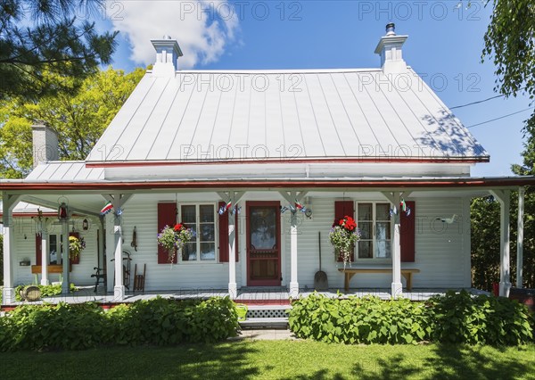 Old circa 1840 white horizontal wood plank with red trim Canadiana style house facade with silver