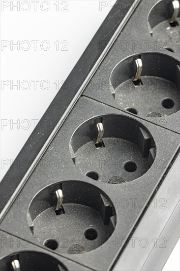 Part of a black plastic socket strip with empty sockets