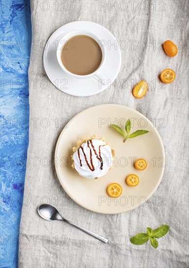 Cake with whipped egg cream on a light brown plate with kumquat slices and mint leaves on a blue