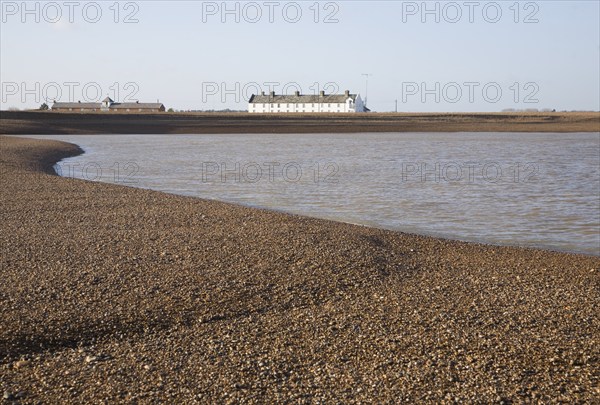 White terrace of Coastguard Cottages, beach and sea viewed from offshore, Shingle Street, Suffolk,