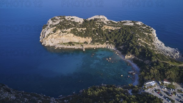Aerial view of a green, peaceful bay with clear water, steep cliffs and far-reaching ocean under a
