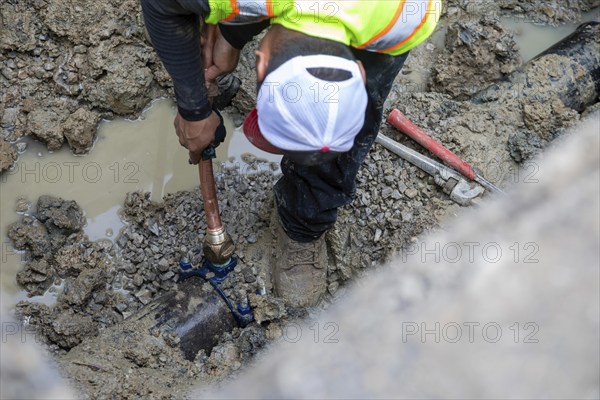 Detroit, Michigan, A new copper pipe is connected to the underground water main as workers replace
