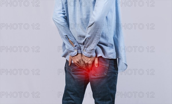 Man with digestive problem touching his buttock, man with hemorrhoid problem on isolated