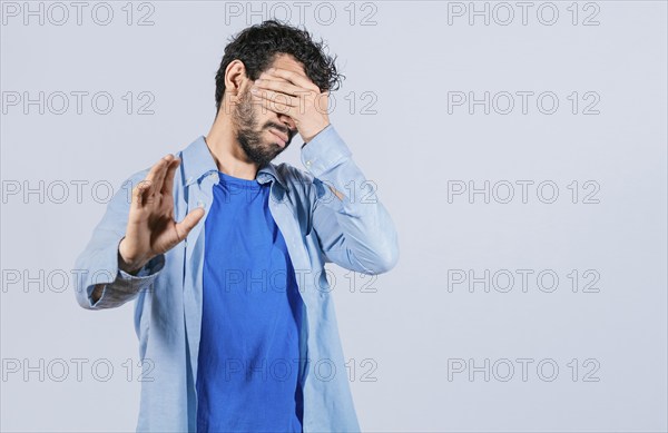 Scared confused man closing eyes with palm of hand isolated
