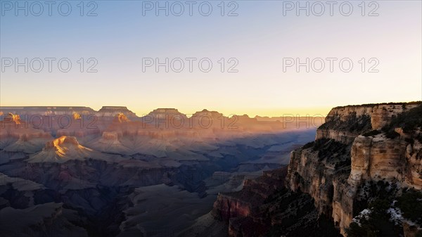 Sunrise over grand canyon in vibrant colors casting light on overhanging rock formations, AI