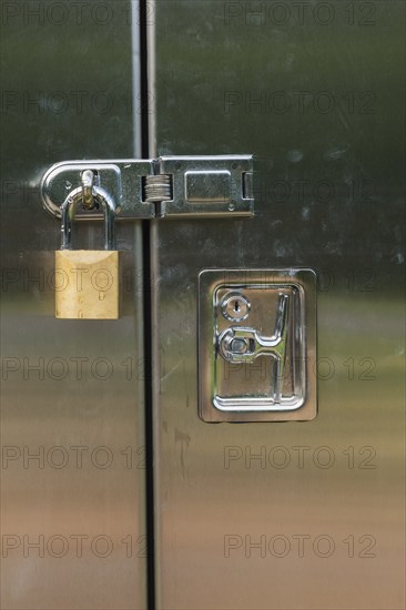 Close-up of stainless steel door on a utility cabinet locked with a brass padlock, Quebec, Canada,