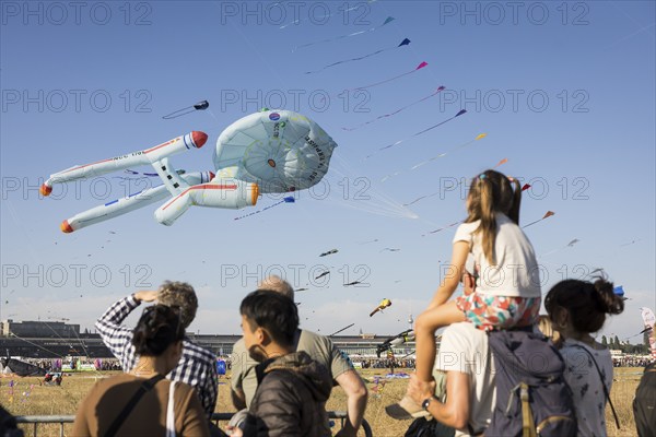 Visitors watch flying kites, including in the shape of the USS Enterprise, in front of the Berlin