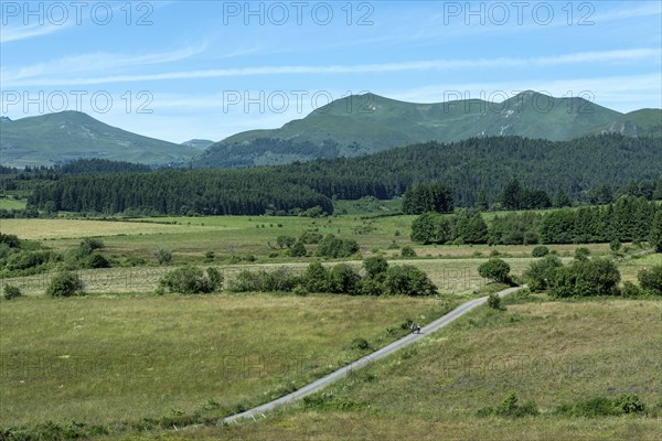 Hikers stroll along a path at the foot of the Monts Dore in the picturesque Auvergne Volcanoes