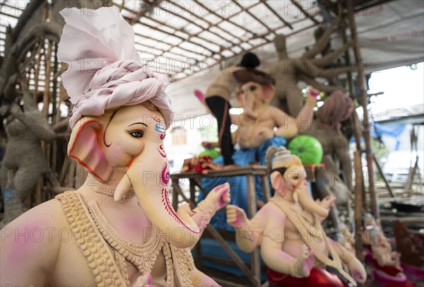 An artisan decorates an idol of the elephant-headed Hindu deity Ganesha at a workshop ahead of the