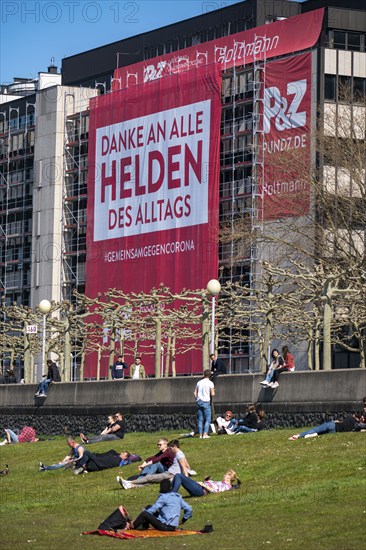 A construction company has hung a large poster on a building facade on the Rhine promenade,