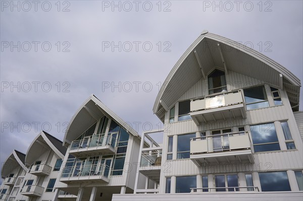 A modern residential building with several balconies and glass fronts under a cloudy sky, Molde,