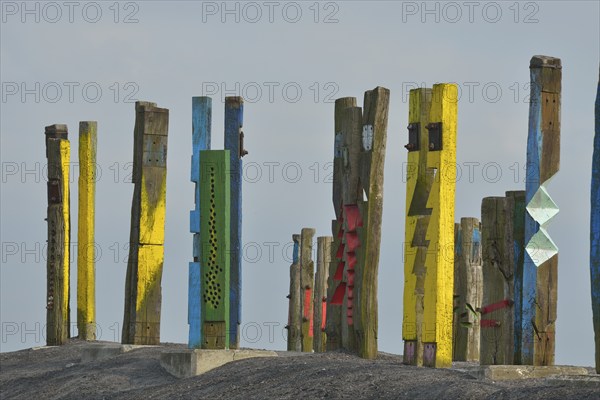 A creative art installation of colourfully painted wooden posts with abstract patterns against a