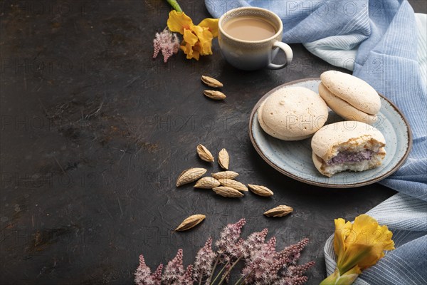 Meringues cakes with cup of coffee on a black concrete background and blue linen textile. Side