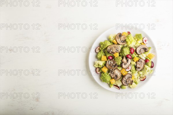 Vegetarian salad from romanesco cabbage, champignons, cranberry, avocado and pumpkin on a white
