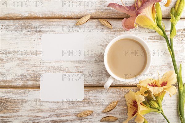 White paper business card mockup with orange day-lily flower and cup of coffee on white wooden