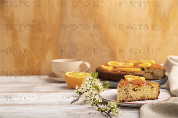 Orange cake and a cup of coffee on a white wooden background and linen textile. Side view, copy