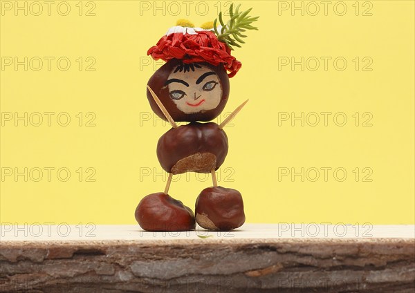 Funny chestnut figure with hat standing in front of a yellow wall, North Rhine-Westphalia, Germany,