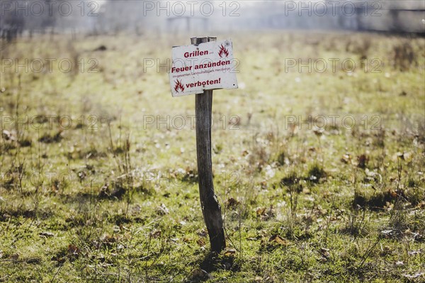 A sign with the inscription 'Barbecues and lighting fires prohibited' stands in a meadow in Berlin,