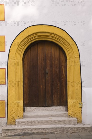 Old wooden entrance door with doorstep and yellow contour on facade of Stadtsall hotel building in