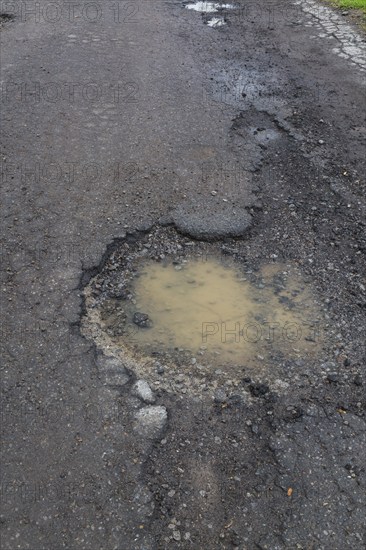 Pothole filled with rainwater on wet black asphalt road surface in spring, Montreal, Quebec,