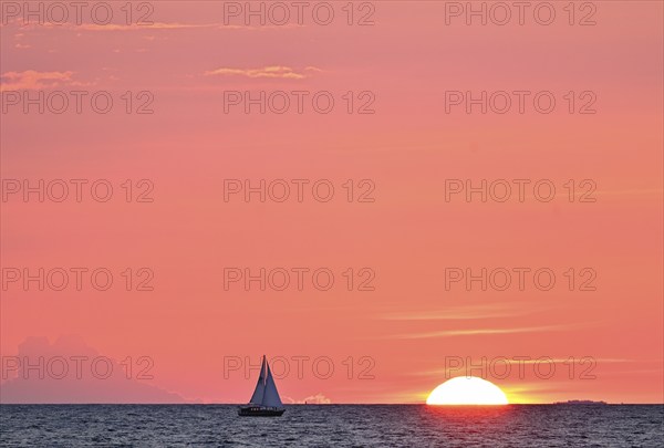 Sailboat sailing in the evening towards the setting sun, Baltic Sea, Poel Island,