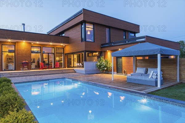 Rear of modern cube style home with stained horizontal wood cladding, in-ground swimming pool and