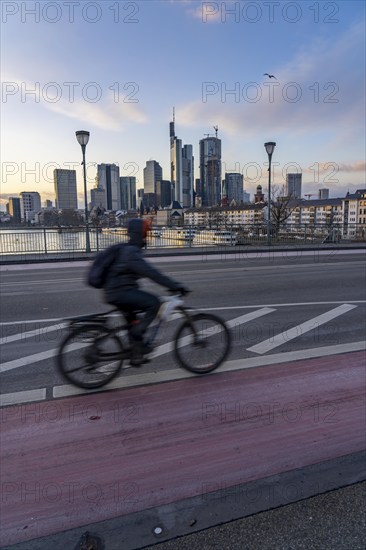 Skyline of the city centre of Frankfurt am Main, cyclist on the Ignatz-Bubis-Bridge, dusk, river